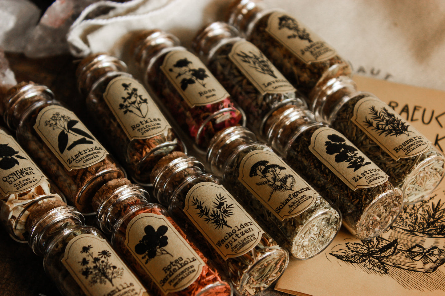 12 Räucherungen, Edition II - Räucherwerk - Geschenkset Harz Hausräucherung, 12 kleine Gläser mit verschiedenen Kräutern, präsentiert auf einem gelben Booklet und einer kleinen Tasche