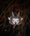 Vor einem Mistelstrauch hängt an einem roten Faden mit Glöckchen ein Holz-Ornament, das den niedlichen Kopf eines Krampus mit langer roter Zunge und Hörnern eingebrannt hat.