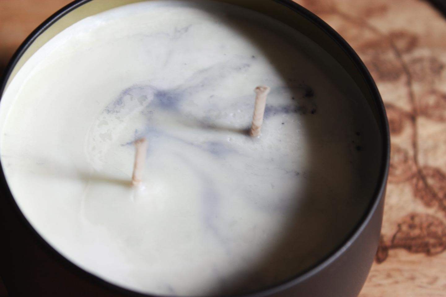 Das Bild zeigt eine Nahaufnahme einer Kerze mit zwei Dochten. Die weiße und blaue Wachsfarbe ergibt ein himmel-artiges Muster.