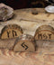 Drei Kartenhalter aus Holz stehen auf einem Holztischchen. Die Kartenhalter haben eine rustikale Rinde. Eingebrannt haben sie verschiedene Runen.