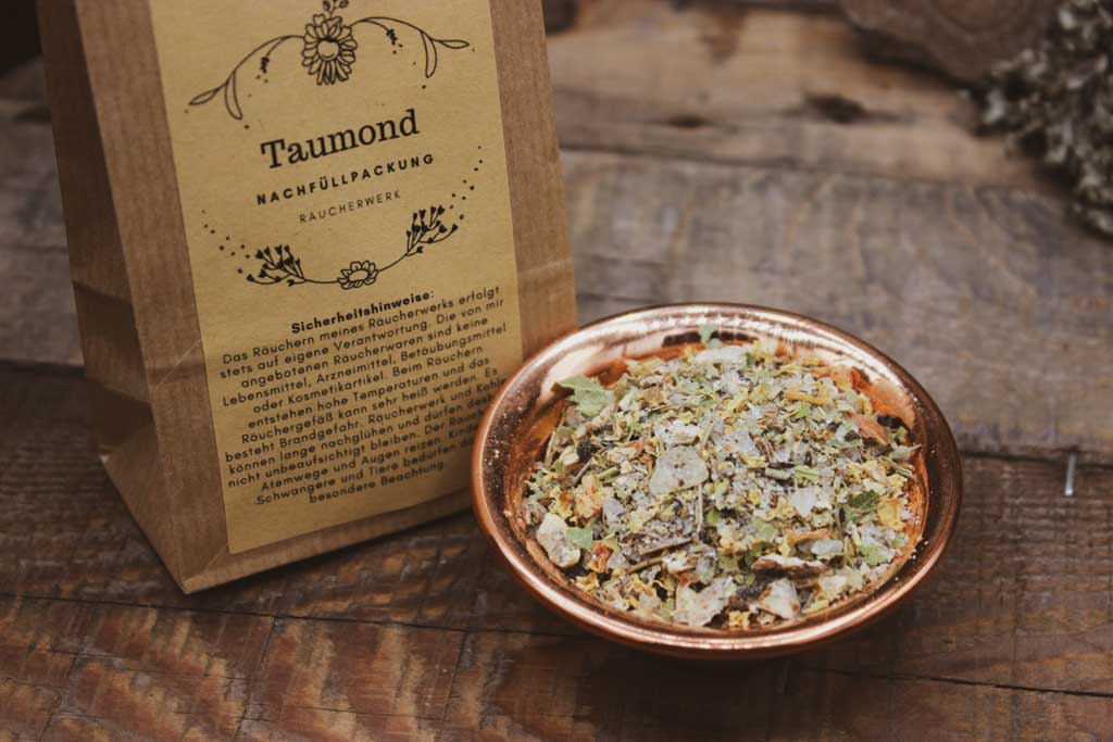 Links steht eine braune Tüte mit dem Taumond Etikett darauf. Daneben steht eine kupferne Schale mit der Räucherung aus Kräutern, Blüten und Harzen zu Imbolc.