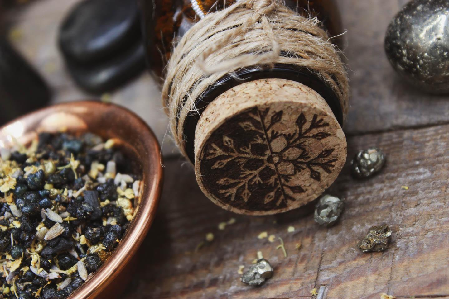 Nahaufnahme des Korkens des Braunglases. In den Korken eingebrannt ist ein Motiv. Es zeigt eine Schneeflocke die auf der einen Seite schwarz und auf der anderen weiß ist.