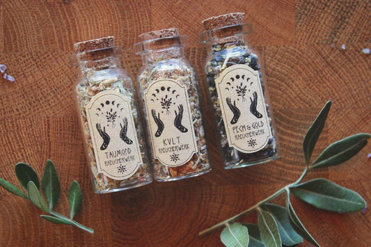 Drei kleine Korkenfläschchen, die mit Räucherwerk gefüllt sind. Von links nach rechts steht auf den Etiketten: Taumond, KVLT, Pech & Gold