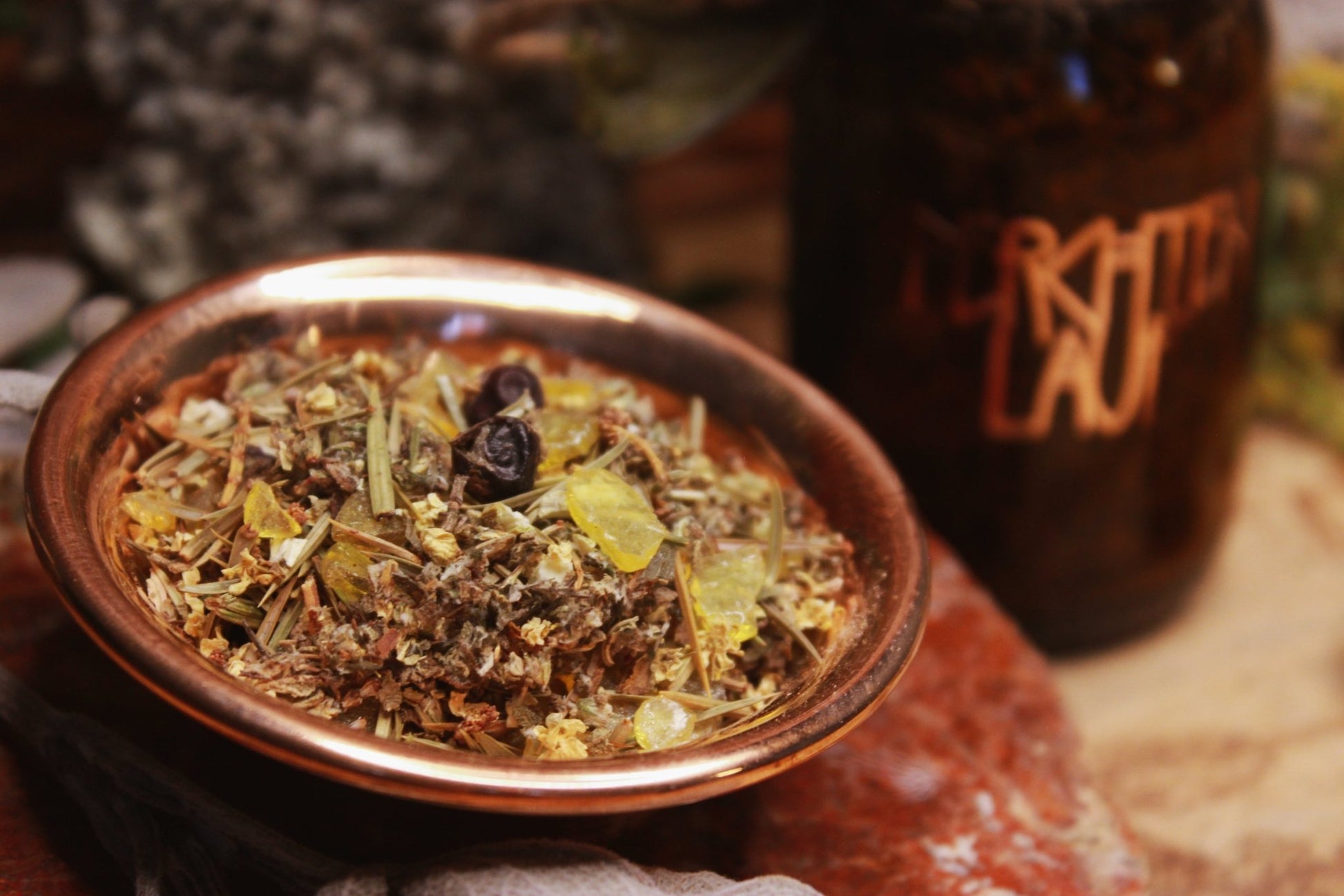Nahaufnahme Räucherwerk Perchtenlauf, Räucherwerk in Glasflasche neben Kupferschale mit getrockneten Kräutern und Harz.