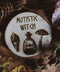 Wandbild aus Holz "Autistic Witch" - Handgefertigte Holzgravur mit dem Text ‘AUTISTIC WITCH’, umgeben von detaillierten Zeichnungen eines Blattes, einer Flasche mit farbiger Flüssigkeit und eines Pilzes. alles ist umgeben von Kräutern und Pflanzen