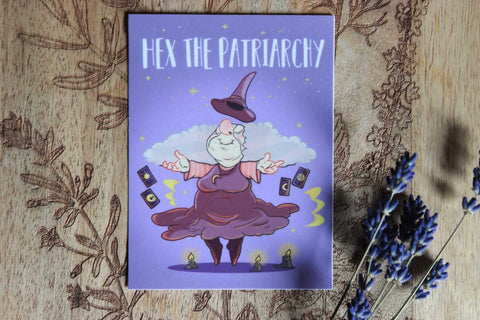 Das hochgeladene Bild zeigt eine Cartoon-Illustration einer älteren Frau, die als Hexe gekleidet in der Luft schwebt und einen zufriedenen Gesichtsausdruck hat. Sie trägt ein lilafarbenes Kleid sowie einen spitzen Hut, der über ihrem Kopf schwebt. Um sie herum sind vier Tarotkarten zu sehen sowie drei brennende Kerzen, die auf dem Boden stehen. Der Hintergrund ist in einem hellen Lilaton gehalten und zeigt Sterne und Wolken.

Oben im Bild steht in großen weißen Großbuchstaben „HEX THE PATRIARCHY“.