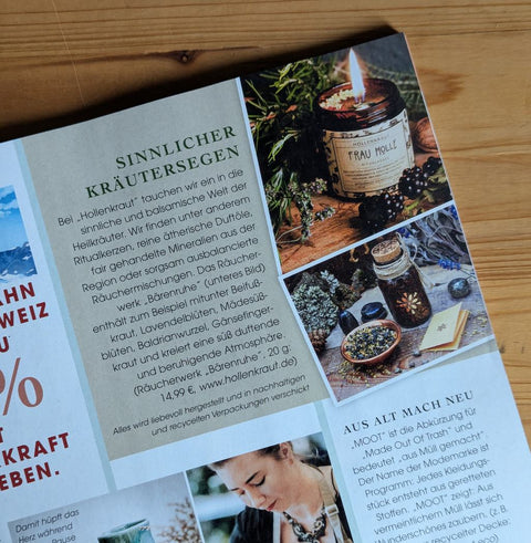 Ein Ausschnitt aus einer Magazin-Seite. Zu sehen ist ein hellgrüner Kasten mit Text und daneben zwei Fotos. Das obere Foto ist eine Kerze in einem Braunglas. Sie brennt. Auf dem Etikett der Kerze steht: Frau Holle
Das Bild darunter zeigt eine Braunglas-Flasche mit Korken. Daneben steht eine kupferne Schale mit Räucherwerk darin.
Der Text lautet: Sinnlicher Kräutersegen
Bei "Hollenkraut" tauchen wir ein in die sinnliche und balsamische Welt der Heilkräuter. (...)