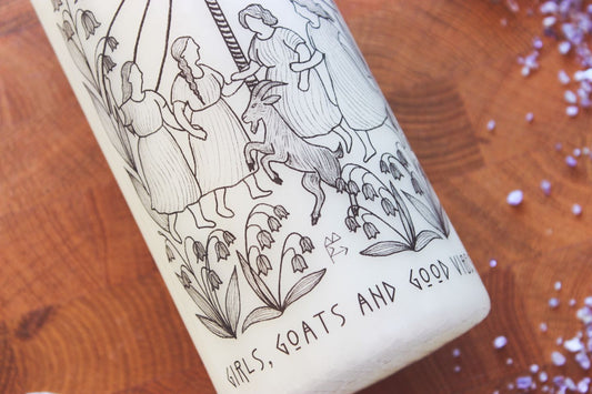 Detailbild des unten Teils der Kerze. Der Fokus ist hier auf dem auf den Hinterbeinen stehen Ziegenbock und der Schrift, sowie auf den Maiglöckchen. In der Mitte ist eine Runen-Sigille zu sehen.