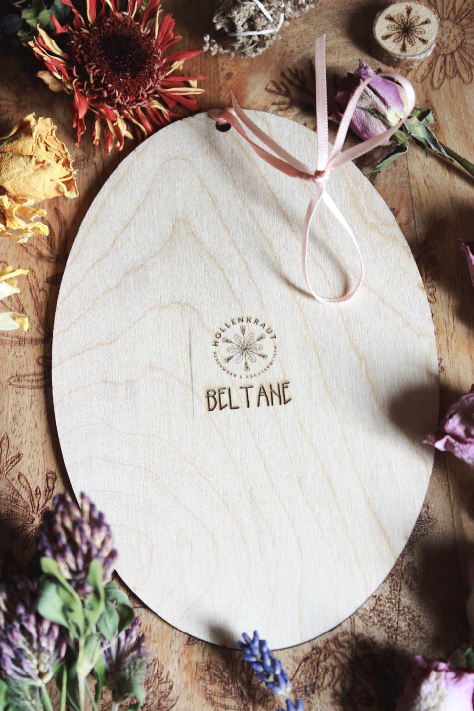 Die Rückseite des Ornaments. Auf der Holzplatte ist das Hollenkraut-Logo graviert und darunter steht: Beltane