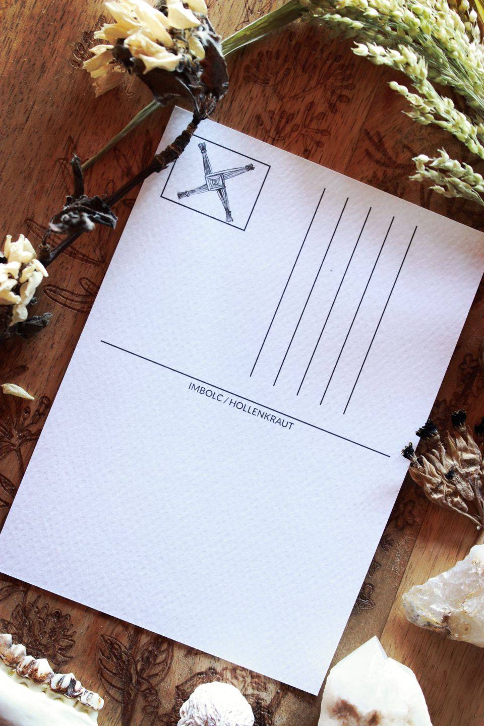 Die weiße Rückseite der Postkarte hat Hilfslinien für die Anschrift aufgedruckt. In der Ecke ist ein Rechteck für eine Briefmarke. Dort ist das Kreuz der Brigid aufgedruckt.