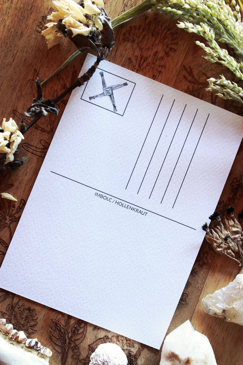 Die weiße Rückseite der Postkarte hat Hilfslinien für die Anschrift aufgedruckt. In der Ecke ist ein Rechteck für eine Briefmarke. Dort ist das Kreuz der Brigid aufgedruckt.
