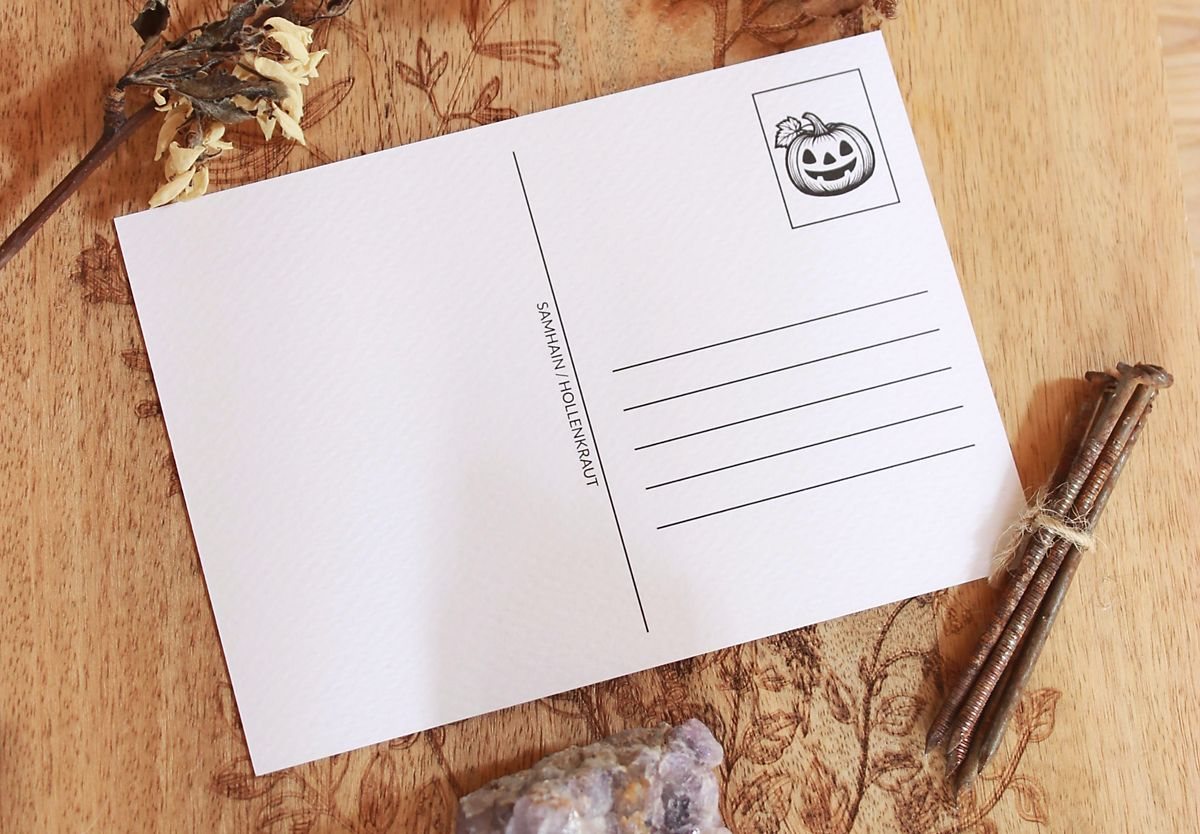 Die Rückseite der Karte in weiß mit schwarzer Schrift. Rechts oben ist ein grinsender Kürbis. In der Mitte steht klein geschrieben: Samhain / Hollenkraut