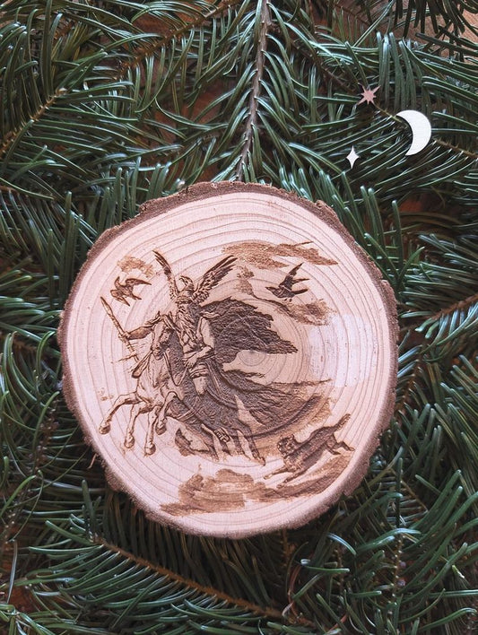 Baumscheibe mit dem eingravierten Motiv von Odin wie er auf seinem Pferd Sleipnir reitet. Gebettet ist das Bild auf Tannenzweigen.