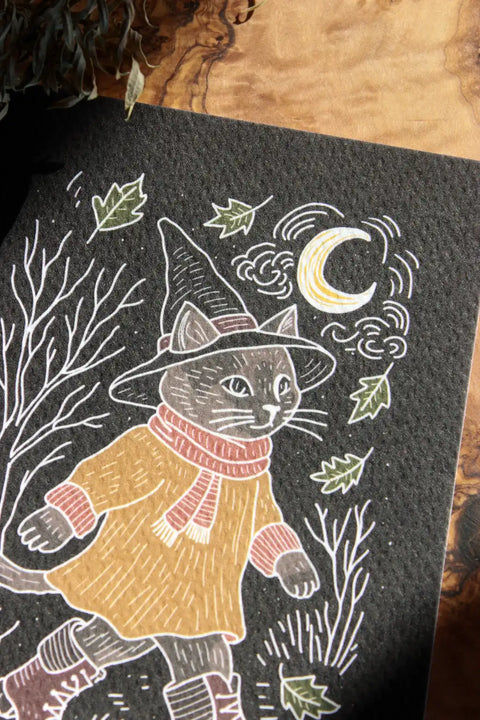 Der Print in näherer Aufnahme zeigt eine Katze mit Hexenhut, die im Mondschein durch eine Herbstlandschaft spaziert.