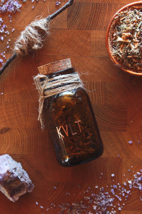 Räucherwerk im Braunglas im Apothekenstil mit Korken: Auf dem Glas steht „KVLT“ in kupferfarbenen Buchstaben, der Korken zeigt drei miteinander verwurzelte Bäume als kreisförmiges Symbol. Naturverbundenes, handgemachtes Räucherwerk für Rituale, Meditation und moderne Hexen.