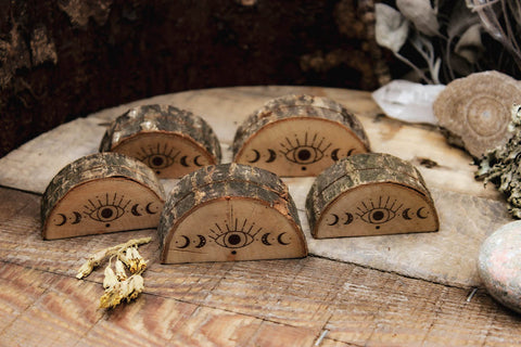 Verschiedene Kartenaufsteller mit witchy Motiven aus Holz mit rustikaler Rinde. Das eingebrannte Bild zeigt ein Auge und die Mondphasen.