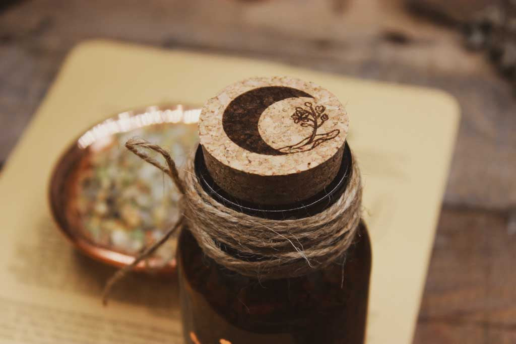 Eine Nahaufnahme des Korkens auf der braunen Flasche. Auf dem Korken ist ein Mond und eine Lindenblüte eingraviert.
