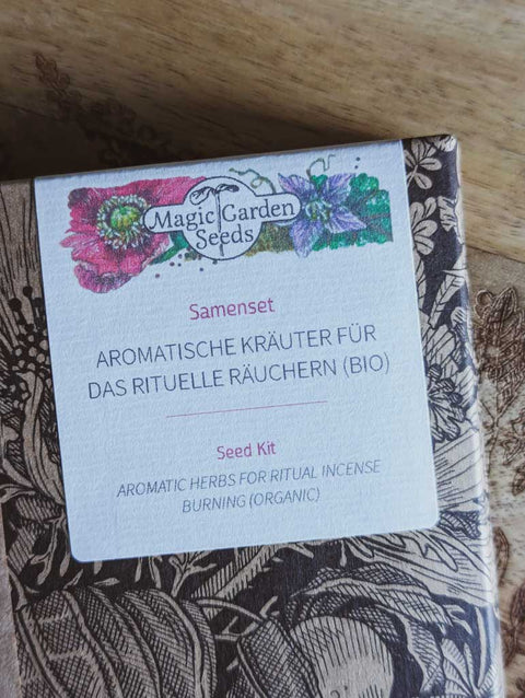 Saatgut Geschenkset in einer schön illustrierten Pappverpackung mit Kräutern und Insekten. Darauf steht: Magic Garden Seeds Samenset Aromatische Kräuter für das rituelle Räuchern - Nahaufnahme