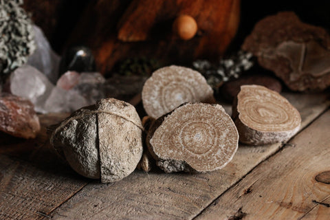 Auf einer rustikalen Holzplatte liegen drei Hälften einer Aragonit-Kugel und eine von einer Juteschnur zusammengehaltene Kugel.